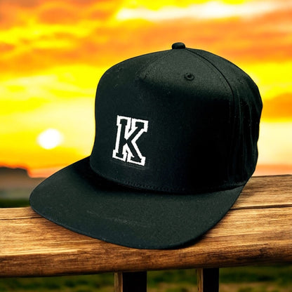 Snapback Baseball Cap mit Wunschbuchstabe, Schwarz mit Weißer Stickerei, Verstellbar